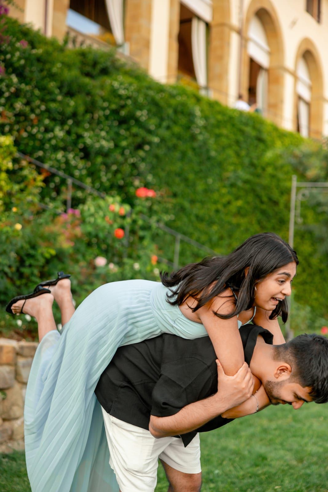 Barun carrying Pooja along a garden path, both of them laughing